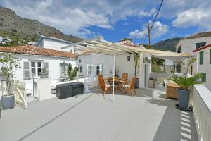 a patio with a table and a white pergola at Pearl House in Hydra