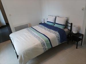 Schlafzimmer mit einem Bett mit blauer und weißer Bettwäsche und Kissen in der Unterkunft O'Couvent - Appartement 44 m2 - 1 chambre - rdc ext in Salins-les-Bains
