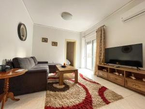 een woonkamer met een bank en een flatscreen-tv bij Asiminas lovely house in Ixia