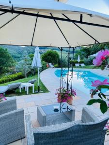 a patio with chairs and an umbrella and a pool at Casale Le Masse in Greve in Chianti