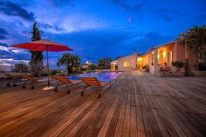 a deck with chairs and an umbrella and a pool at Estate Prophet Elias in Aegina Town