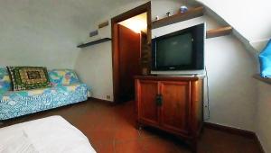 Habitación con TV en un armario de madera y 1 cama. en Portobello's - Work is Vacation, en Albissola Marina