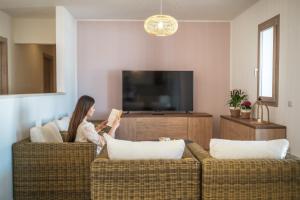 Eine Frau, die auf einer Couch sitzt und ein Buch liest. in der Unterkunft Villa Solymar in Alghero