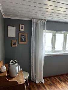 a room with a window with white curtains and a table at Indreli feriehus in Flåm