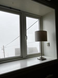 a lamp sitting on a table in front of two windows at Indreli feriehus in Flåm