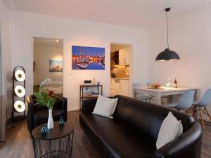 sala de estar con sofá de cuero marrón y mesa en Ohlerich Speicher App. 19 - Meerblick, en Wismar