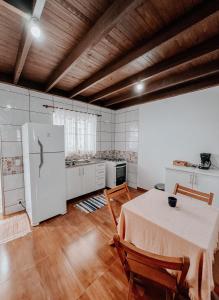 a kitchen with a table and a white refrigerator at Apartamentos Dumont in Monte Verde