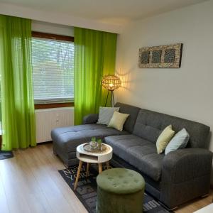 un soggiorno con tende verdi e divano di Erholungs- Apartment am Kurpark & Thermen Bad Urach a Bad Urach