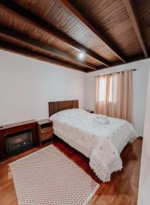 a bedroom with a white bed and a tv at Apartamentos Dumont in Monte Verde