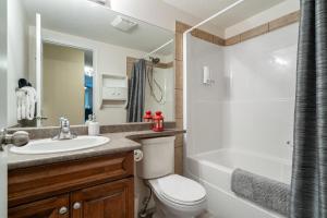 a bathroom with a toilet and a sink and a tub at Polar Peaks Hot Tub Pool Gas Fireplace in Radium Hot Springs +58 photos