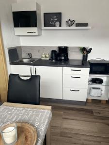 a kitchen with white cabinets and a sink and a table at Ferienwohnung Jardin de lavande in Fridingen an der Donau