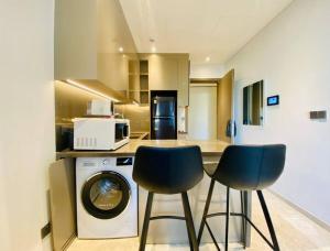 une cuisine avec deux chaises et un lave-linge dans l'établissement The Rixx Iconic Apartment @ D1/pool/gym/Netflix, à Hô-Chi-Minh-Ville