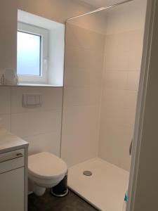 La salle de bains blanche est pourvue d'une douche et de toilettes. dans l'établissement Austernfischer, à Büsum