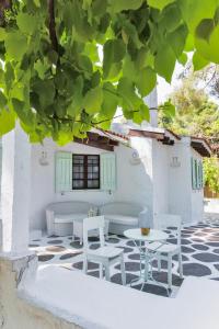 um pátio com cadeiras brancas e mesas debaixo de uma árvore em Villa Nefeli em Sani Beach