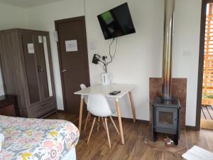 Cette chambre comprend un lit, une table et une cuisinière. dans l'établissement Hospedaje Familiar El Encanto, à Puyehue