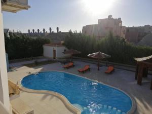 ein Pool mit Stühlen und Sonnenschirmen auf einem Gebäude in der Unterkunft Moubark 6 Studio in Hurghada