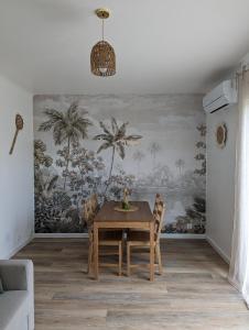 een eetkamer met een tafel en een muurschildering van palmbomen bij L'exotic' 1 à 4 voyageurs in Perpignan