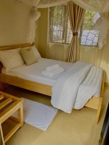 a bedroom with a bed with two towels on it at Golden Cherries Guest House in Jinja