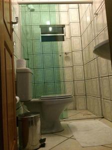 La salle de bains est pourvue de toilettes et d'un mur carrelé vert. dans l'établissement SWAMY HOTEL ANEXO I, à Cruzeiro do Sul