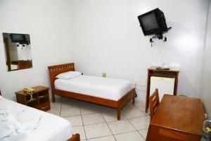 a small bedroom with two beds and a tv at SWAMY HOTEL ANEXO I in Cruzeiro do Sul