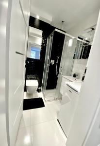 uma casa de banho branca com um WC e um chuveiro em Apartament Akcent em Sopot