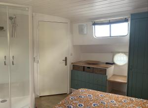 a bedroom with a bed and a window and a shower at Péniche GEMJO in Castelsarrasin