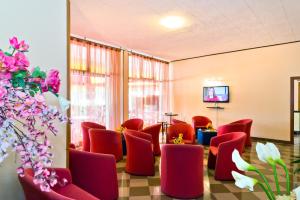 a waiting room with red chairs and a tv at Hotel Corallo in Eraclea Mare