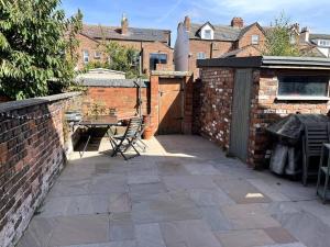 a patio with a table and a brick wall at Stay in the heart of West Kirby in West Kirby