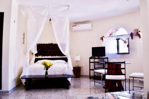 a bedroom with a white bed with a vase of flowers at Hotel Delfin in Playa del Carmen