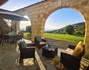 un patio al aire libre con un arco, mesas y sillas en Gaia Residence, Peristerona, Polis Chrysochous, en Pafos