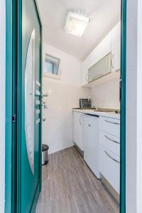 uma cozinha com armários brancos e uma porta verde em Apartman Mauro em Bol