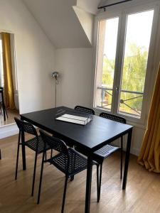 czarny stół i krzesła w pokoju z oknem w obiekcie Appartement Saint Germain en Laye w mieście Saint-Germain-en-Laye