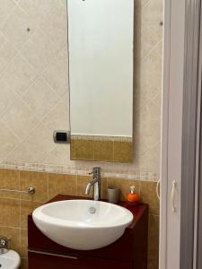 een badkamer met een witte wastafel en een spiegel bij ***** La casa di Giò in Caltanissetta