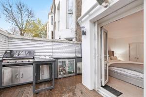 una camera con piano cottura e un letto sul balcone. di Stylish Apartment with BBQ Kensington a Londra