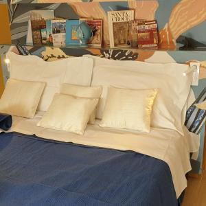 Cama blanca con almohadas blancas y libros en la pared en VILLA LUNA, en Comeana
