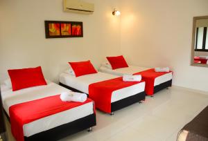 three beds in a room with red and white sheets at Hotel Boutique Duranta in Villavicencio +160 photos