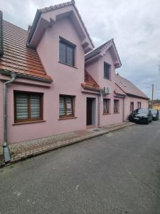 uma casa rosa com carros estacionados na rua em Apartament Nova Kamienica 3 em Łagów