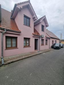 a pink house with cars parked in the street at Apartament Nova Kamienica 3 in Łagów