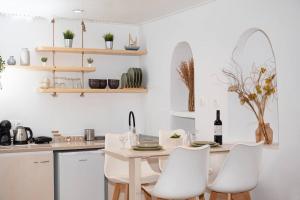 Casa Piccolino في مدينة ميكونوس: مطبخ أبيض مع طاولة وكراسي بيضاء