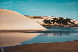 a sand dune next to a body of water at Villas du lac in Soustons