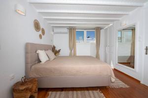 a white bedroom with a bed and a window at Casa Piccolino in Mikonos