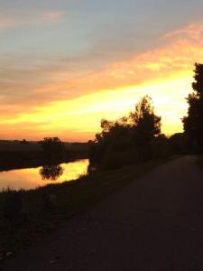 einen Sonnenuntergang über einem Fluss mit Bäumen und einer Straße in der Unterkunft Un Brain de nature in La Chapelle-de-Brain