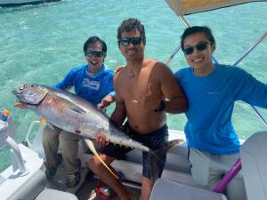 um grupo de três homens em um barco com um peixe grande em Papeete happiness pool and spas em Papeete