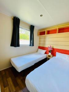 Duas camas num pequeno quarto com uma janela em Bungalow 4x3 em Burinhosa