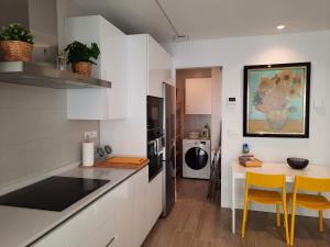 cocina con armarios blancos, mesa y sillas en Apartamento Dindurra Centro Playa, en Gijón