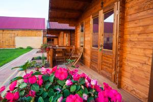 een veranda van een houten huis met roze bloemen bij Pod Lawendą & Jacuzzi & Blisko Augustów in Augustów