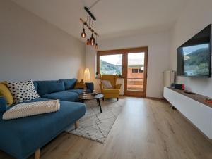 a living room with a blue couch and a tv at Angerpartments-Sonnige große Wohnung mit Balkon und kostenlosen Parkplatz in Döbriach