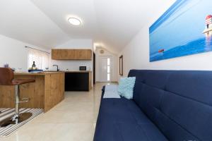 salon z niebieską kanapą i kuchnią w obiekcie Apartmani Valentina w mieście Zadar