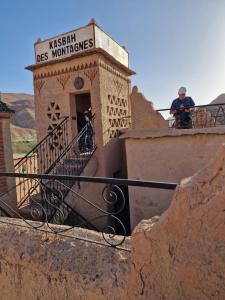 un uomo in piedi sul balcone di un edificio di Kasbah des montagnes maison d'hôtes a Bou Drarar