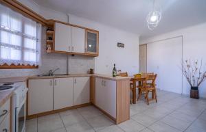 une cuisine avec des placards blancs et une table avec des chaises dans l'établissement Lavender Home, à Sifnos